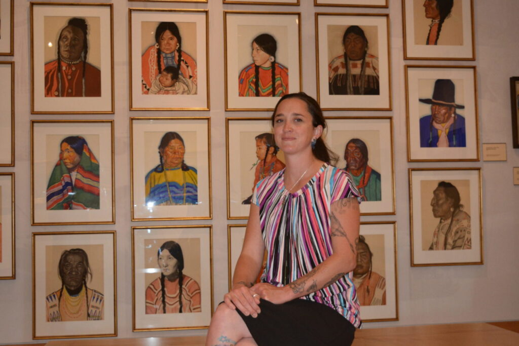 Denica Shell photo in front of pictures on a wall.