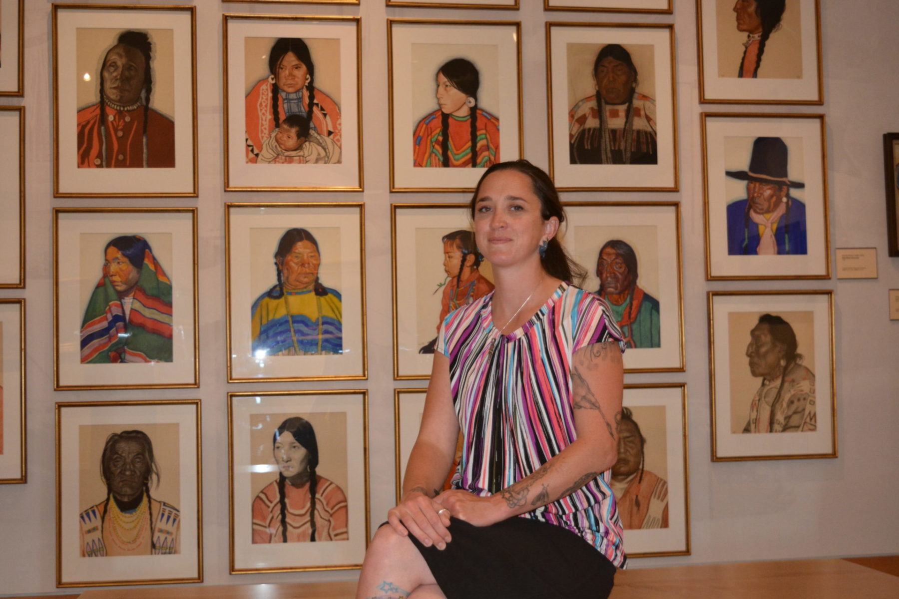 Denica Shell photo in front of pictures on a wall.