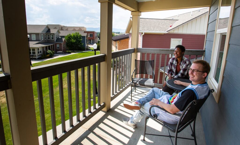 Sheridan College students sitting on the second-story balcony admiring the view of campus.