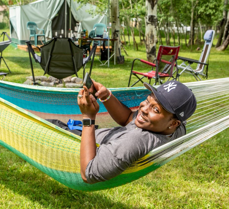 Sheridan College student lying in hammock on his phone.