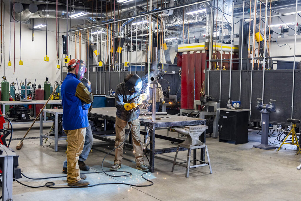 Instructor showing welding students a technique in the welding shop