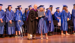 Sheridan College HiSET graduation photo of new graduate excepting her diploma from President Tribley.