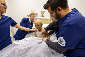 nursing students giving oxygen to hi fidelity maniken during a simulation exercise.
