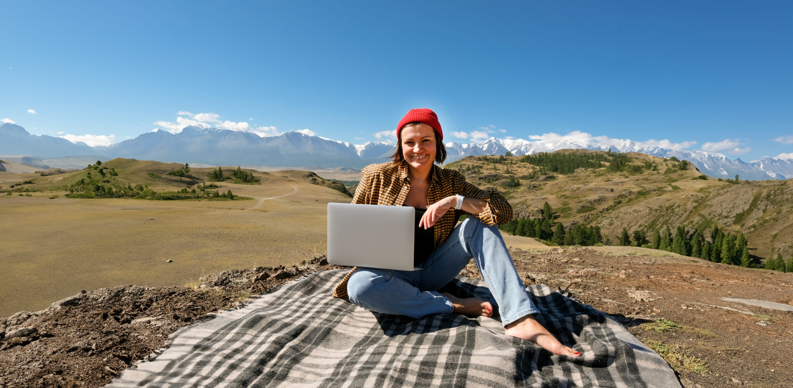 Student sitting with laptop at base of mountains