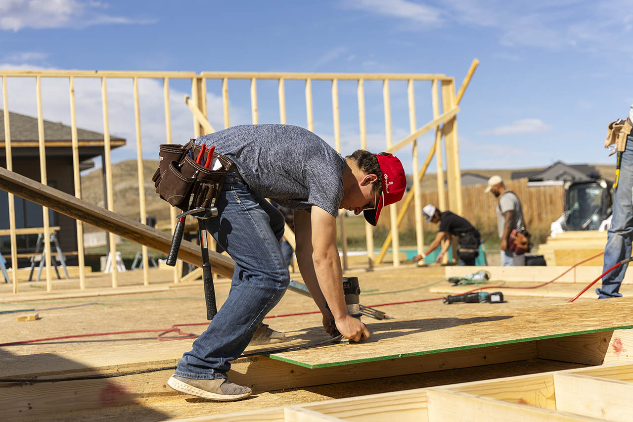 Construction student using a power tool while building outside