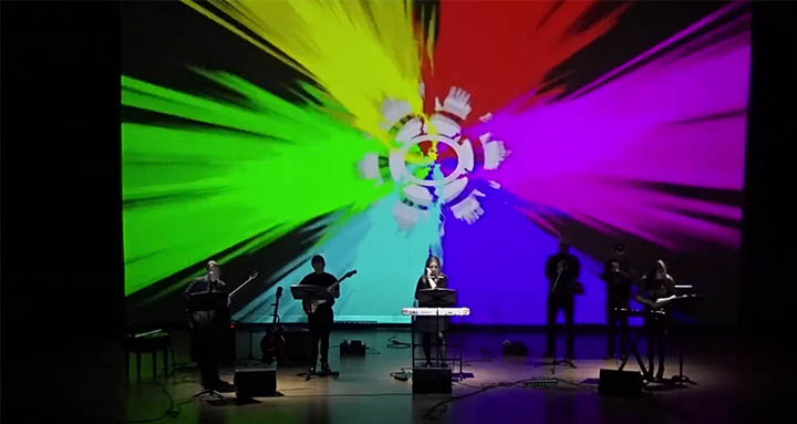 PRISM 2025 performance image with a rainbow of color and light behind the performers
