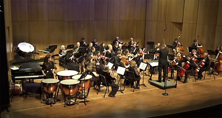 symphony orchestra on stage with conductors arms up