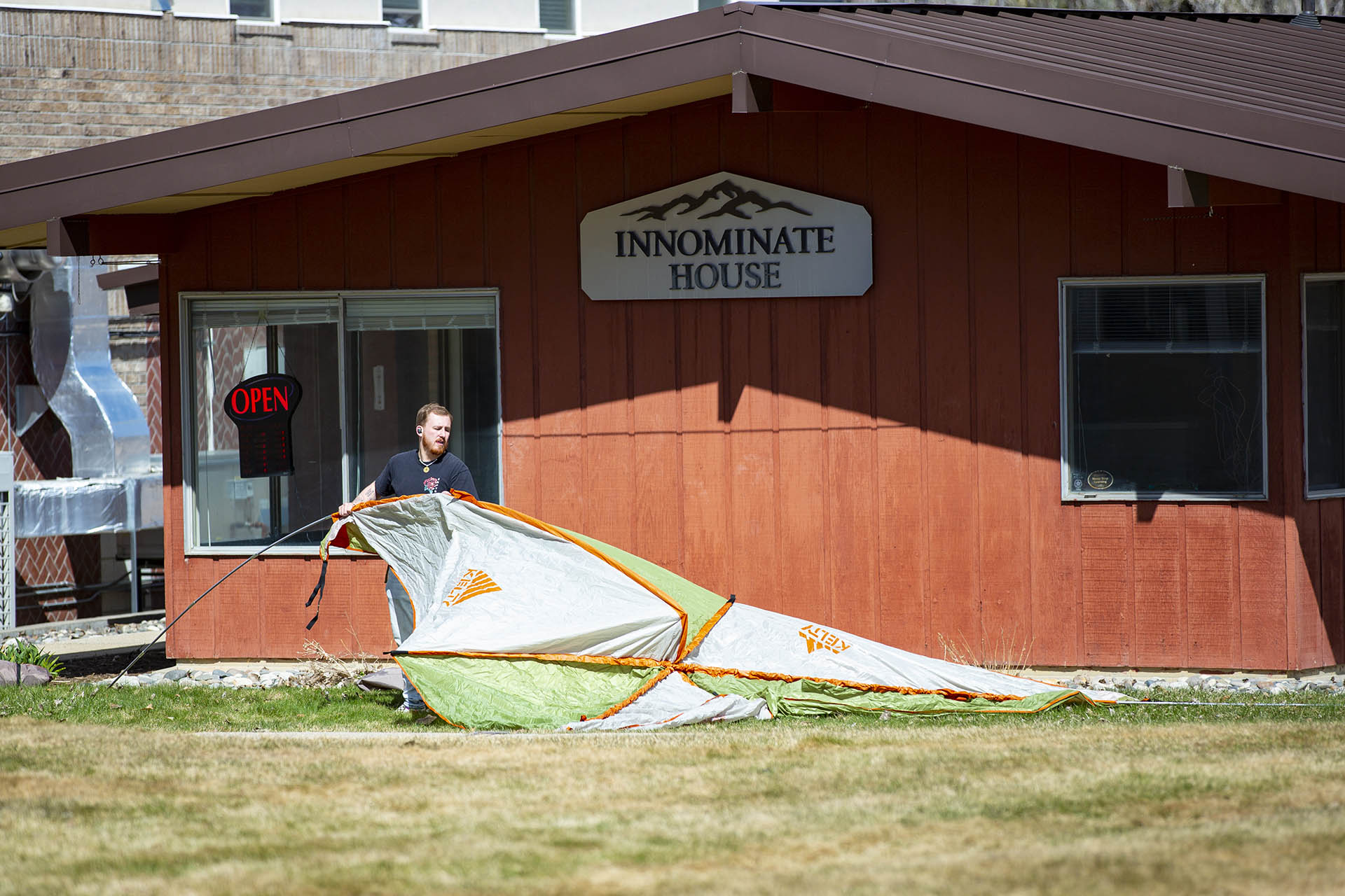 Photo of a student setting up a tent outside the Innominate House at Sheridan College