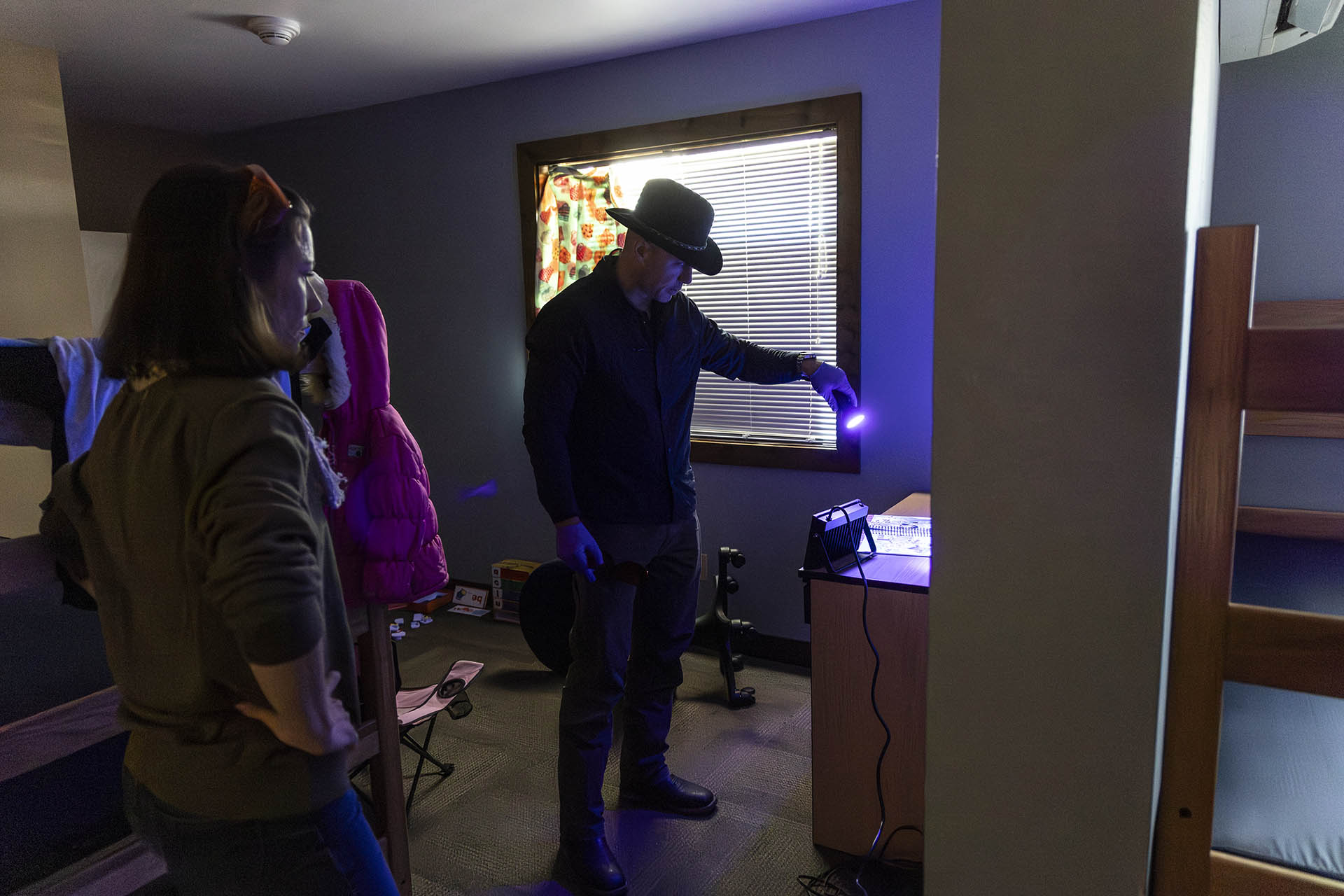 Criminal Justice students using blacklight in a mock crime scene to learn detective techniques