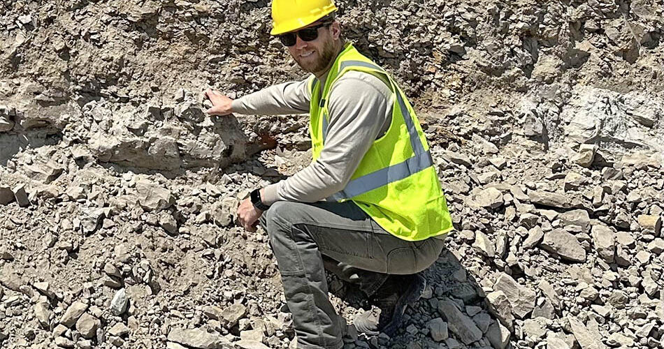 Image of Alex Moyes working with a hard hat and yellow vest likely in a mine site.