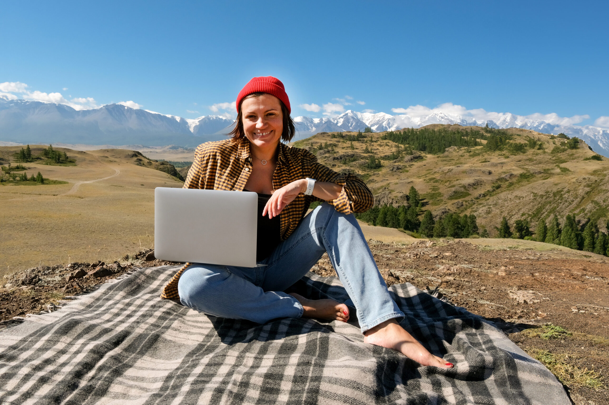 Student sitting with laptop at base of mountains