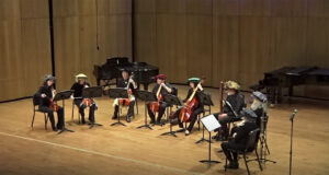 Photo of several musicians in a half circle performing on stage.