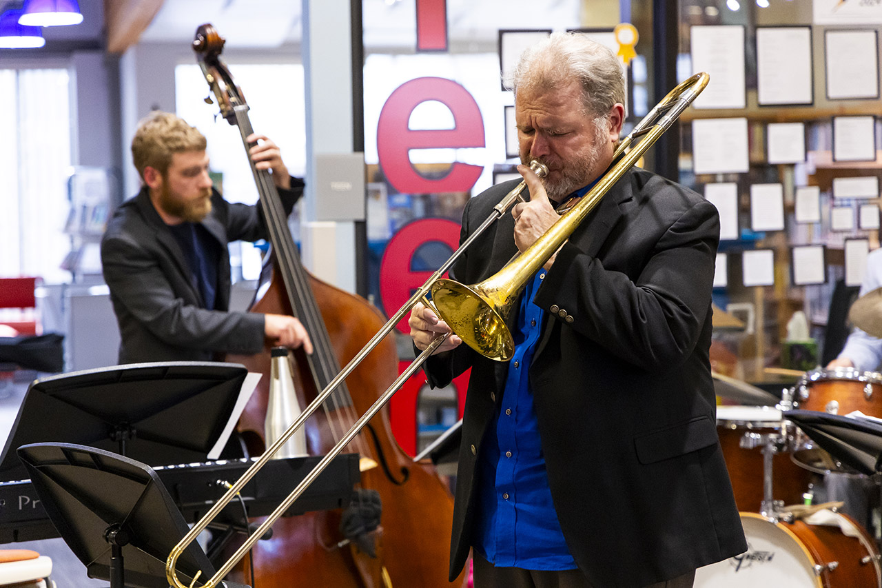 Eric Richards playing trombone with Nick Lulias in the background on upright bass