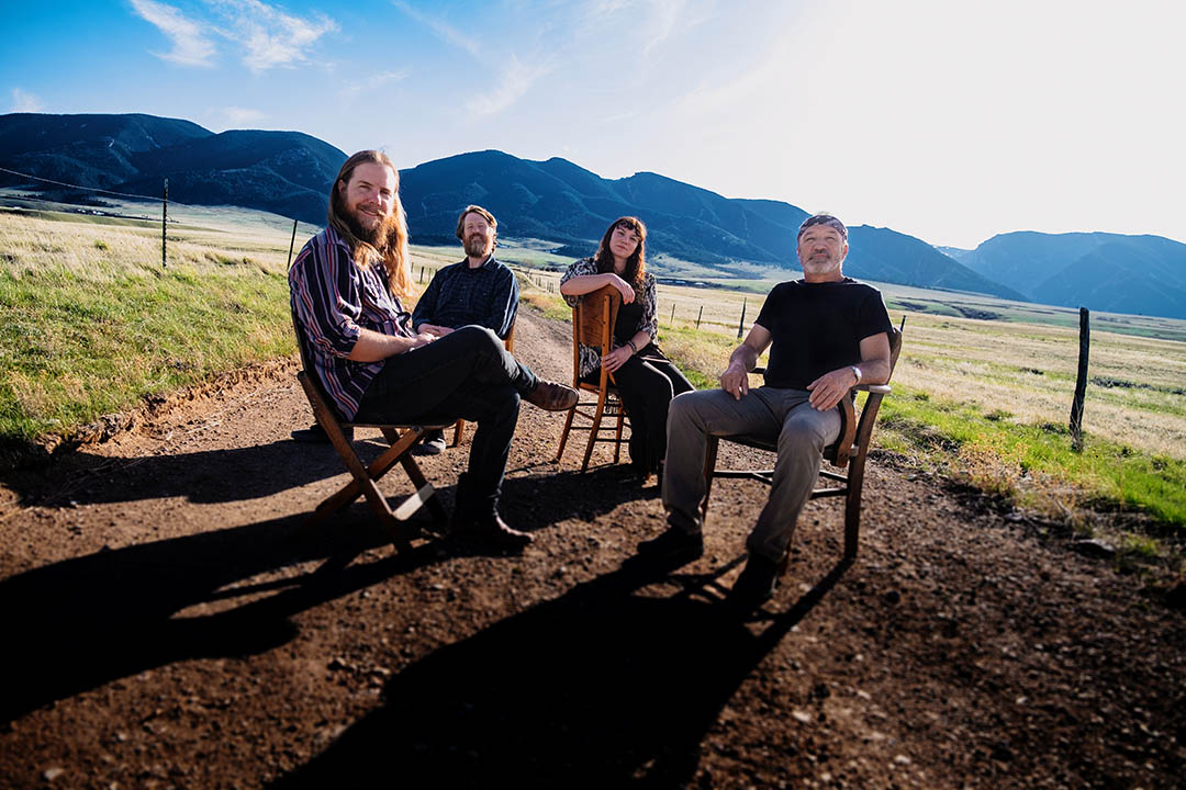 Photo of the four members of The Two Tracks outside with the Bighorn Mountains behind them
