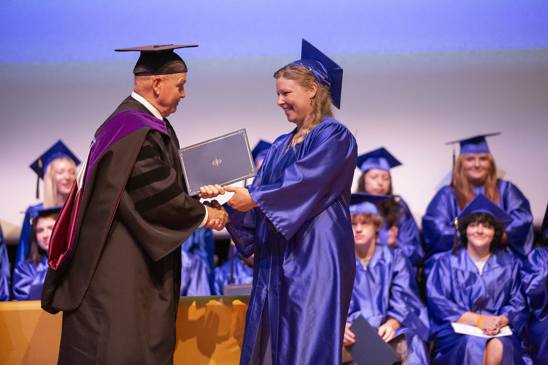 Image of an adult education graduate accepting their HiSET diploma from president Tribley