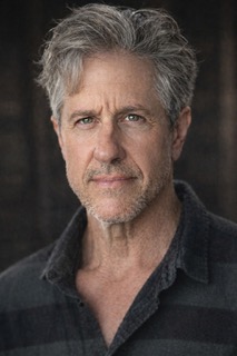 headshot photo of Michael Berry wearing a dark shirt with greying hair.