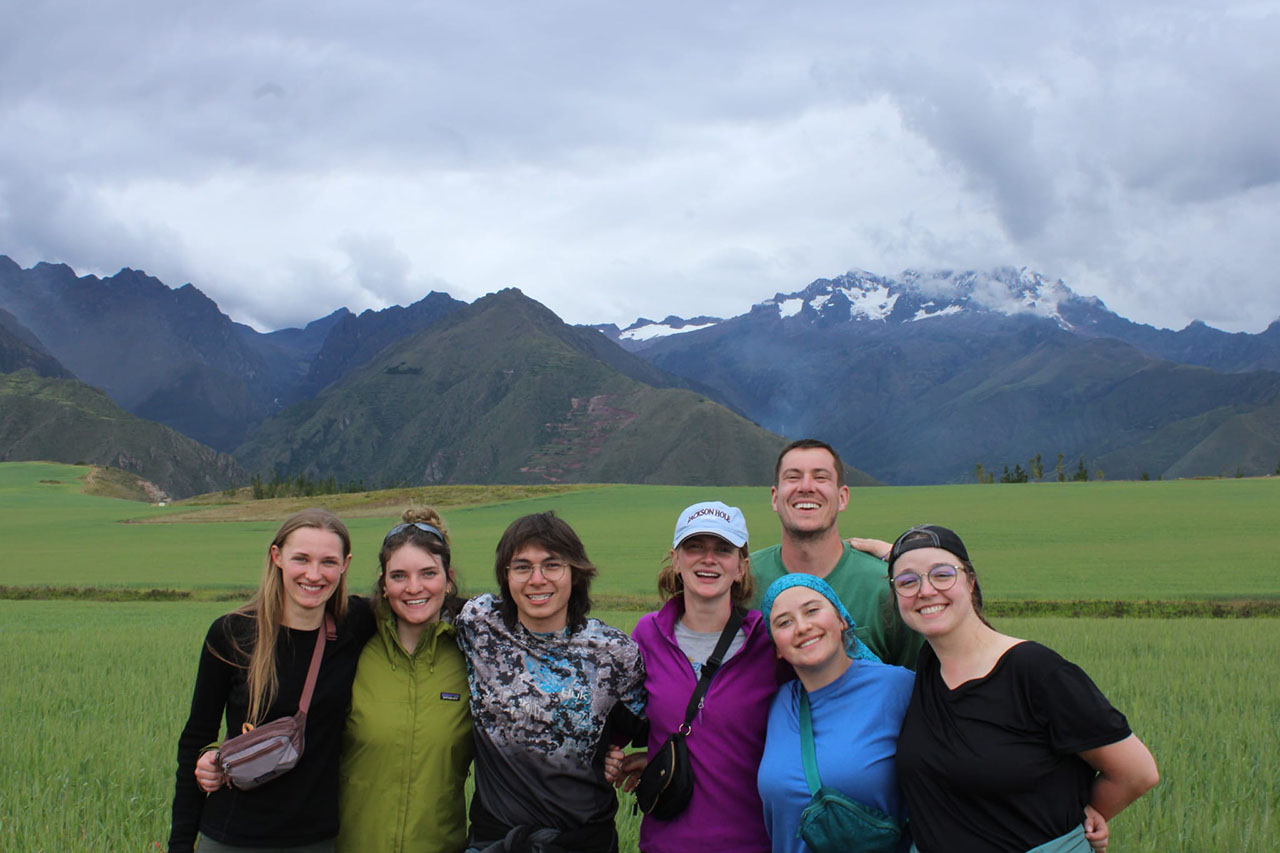 Sheridan College TRIO students posing for a photo with mountains and green grass behind them
