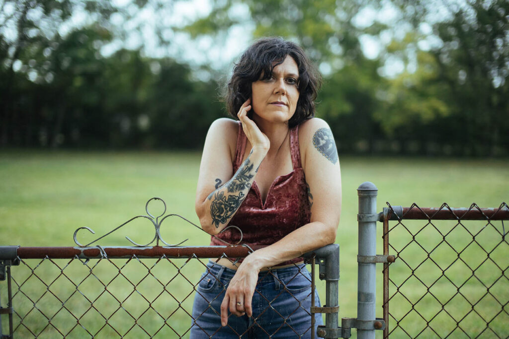 photo of Lilly Hiatt leaning on a chain link fence